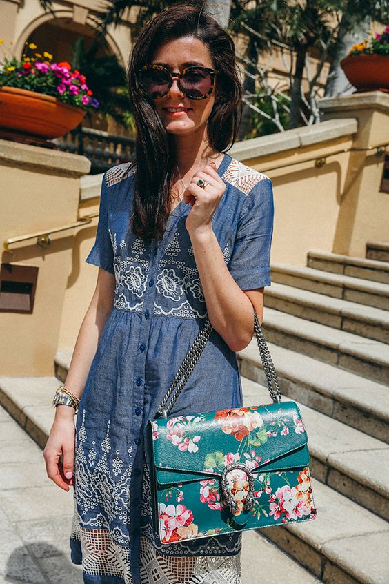 a chambray shirt dress with crochet lace and buttons and a large emerald floral bag