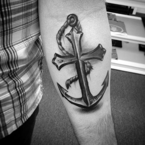 cross anchor tattoo with a memorable date on a forearm