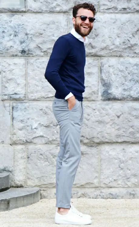 grey pants, a navy sweater, a white shirt and white sneakers
