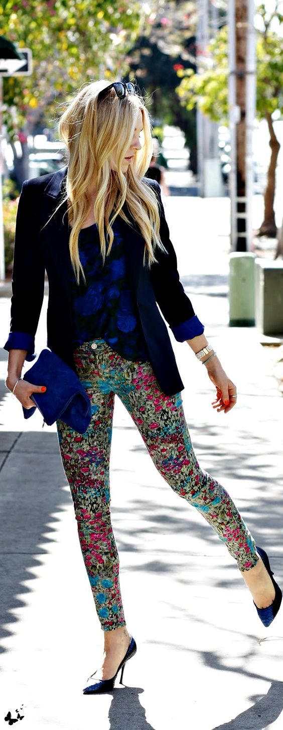 a bold blue floral shirt, a black jacket, colroful floral pants and bold blue heels