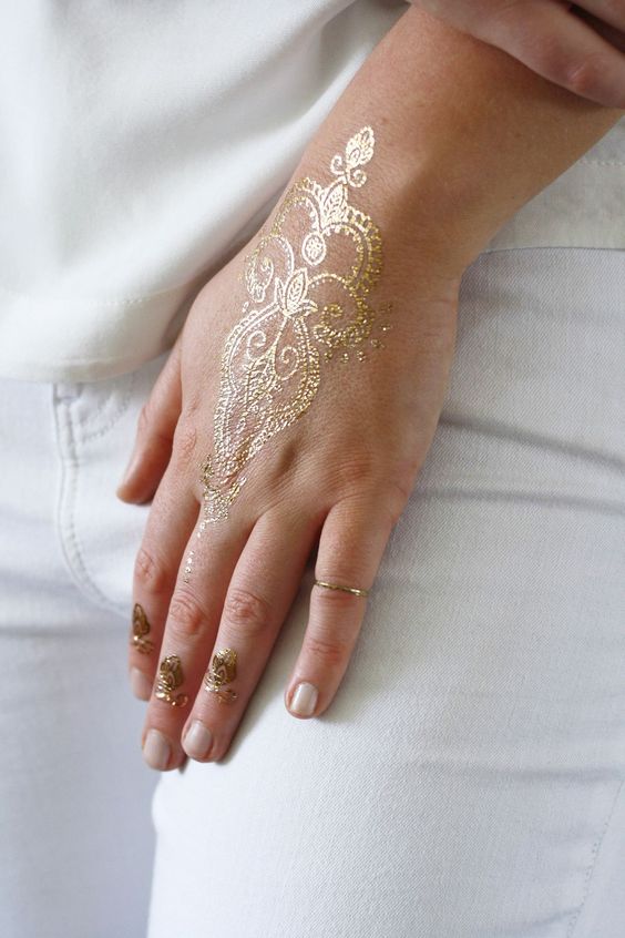 delicate gold henna tattoo on the hand and fingers