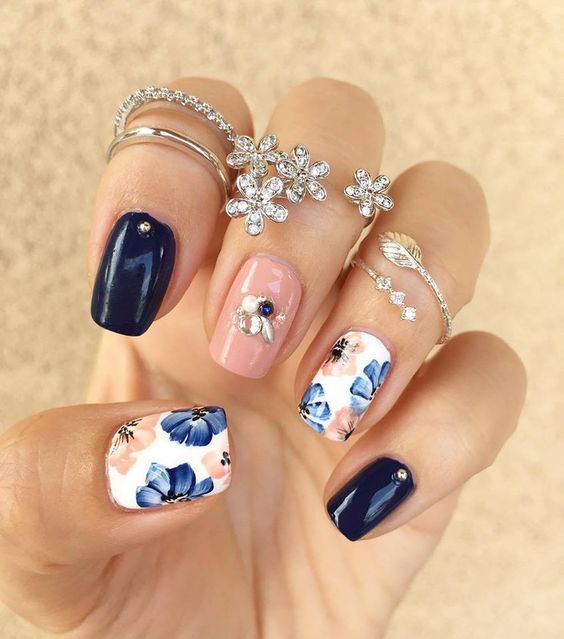navy and peach glossy nails with rhinestones and two floral nails in blue and peach