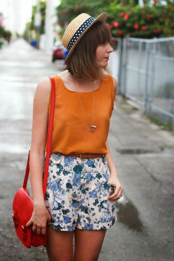 a bold orange sleeveless top and blue floral shorts