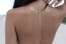 16 gold and white geometric henna tattoo on the upper part of the back