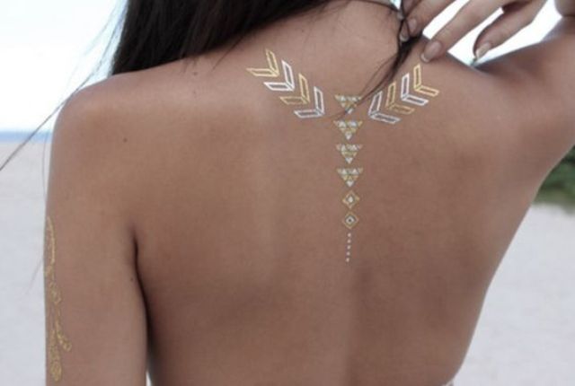 gold and white geometric henna tattoo on the upper part of the back