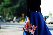 With black shirt, black pumps and colorful clutch