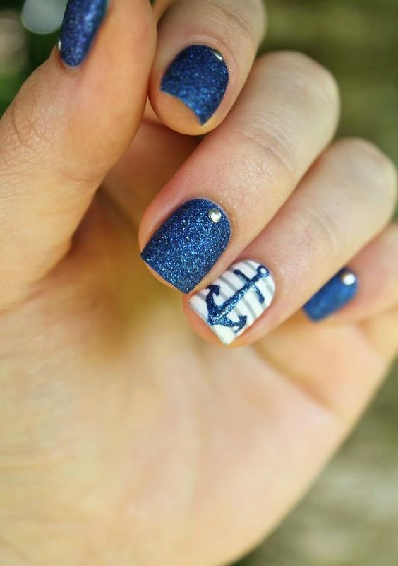 navy glitter nails with rhinestones and a striped accent nail with an anchor
