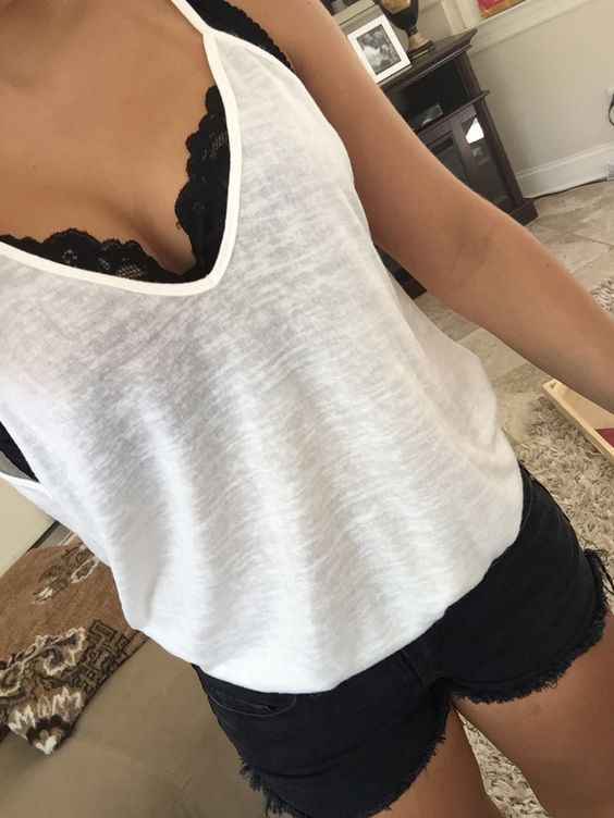 a black lace bralette under a semi sheer white top with black denim shorts