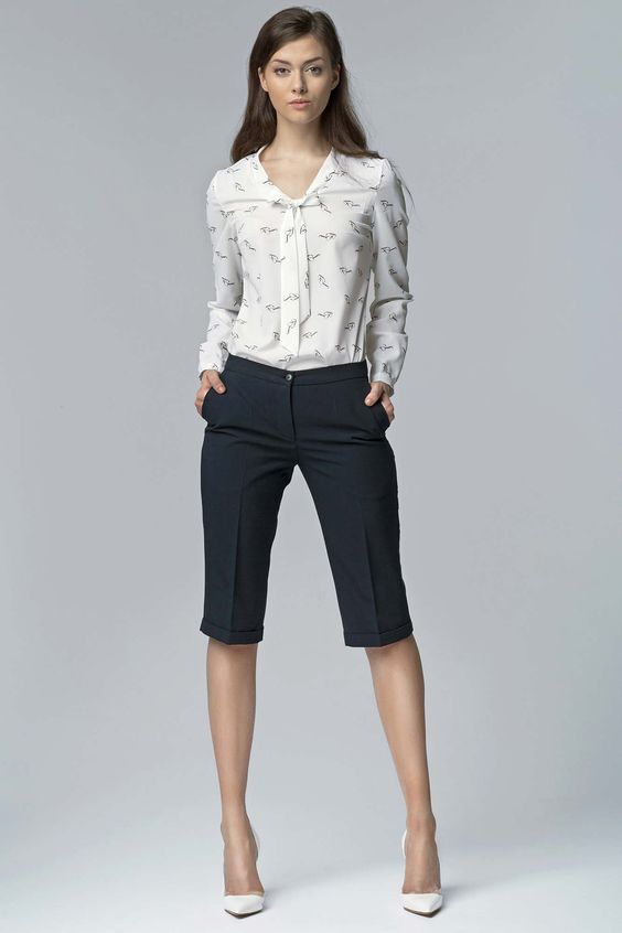 black bermuda shorts, a printed blouse and white pumps for a polished look