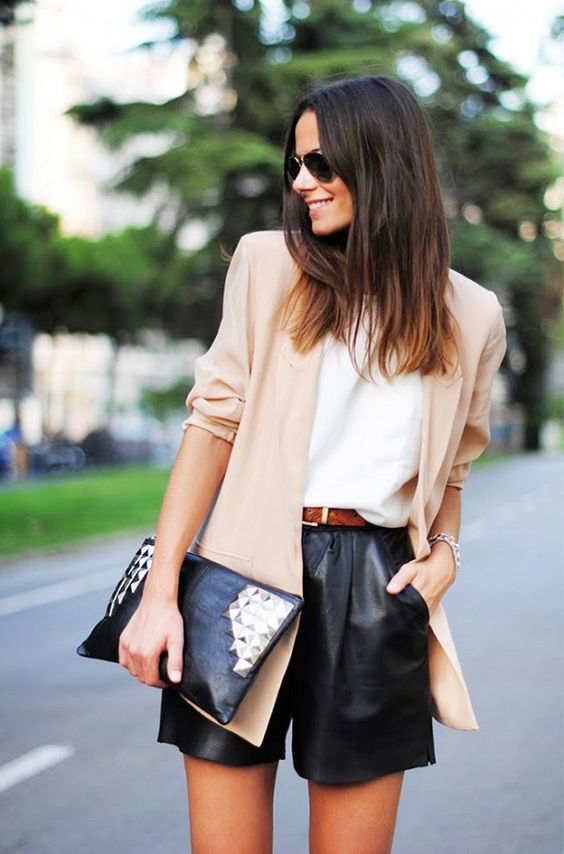 black leather shorts, a white top, a beige blazer and a studded clutch