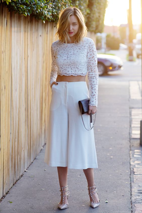 a lace long sleeve crop top and culotte pans, spike shoes and a black clutch