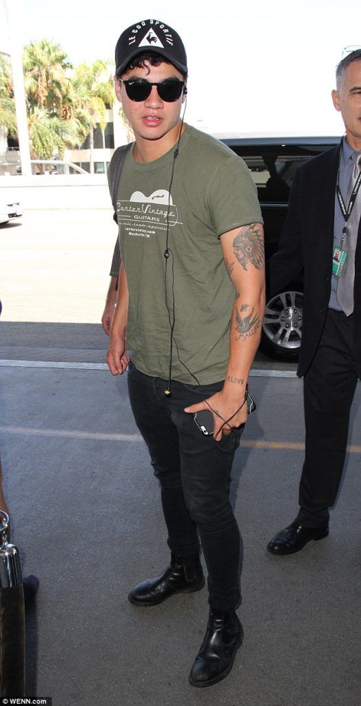 black jeans, black leather boots and an olive green t-shirt and a cap