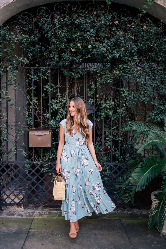 a blue maxi dress with a pink floral print, heeled sandals and a straw bag