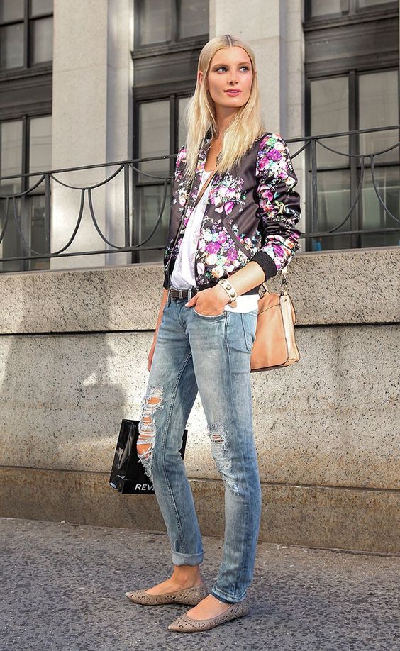distressed jeans, a white lace top, a black floral print bomber, a neutral bag and laser cut flats