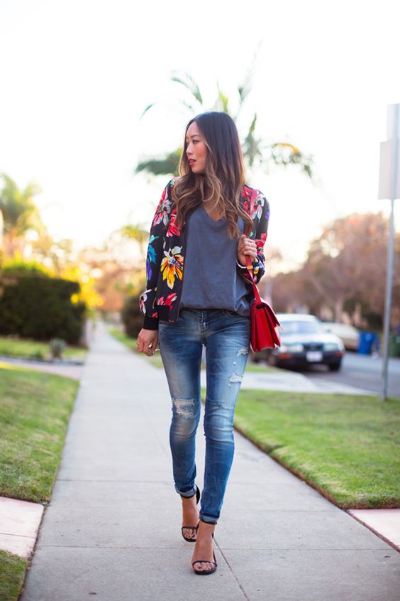 ripped jeans, black heels, an oversized grey tee, a black floral print jacket and a red bag