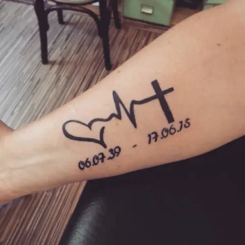 Heartbeat with heart and cross tattoo on the arm