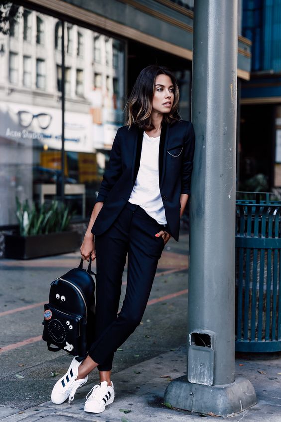 a black tuxedo with cropped pants, a white tee, white sneakers and a black backpack