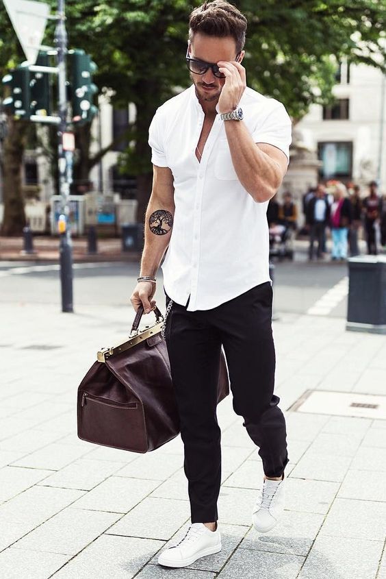 a white shirt with short sleeves, black pants, white chucks and a travel bag