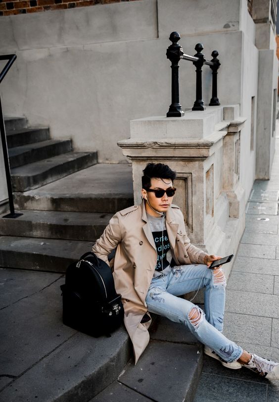 a casual fall look with a beige trench, ripped jeans, sneakers and a grey t shirt