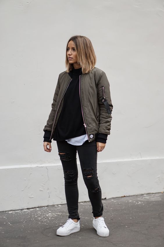 ripped black jeans, a black sweater, a white tee, white sneakers and an olve green bomber
