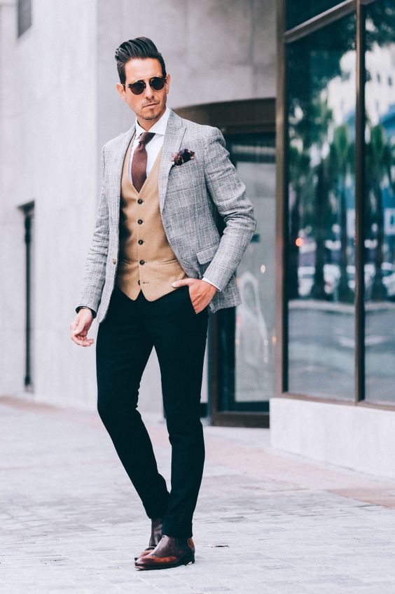 black pants, am amber vest, a white shirt, a brown tie and a grey jacket highlighted with cognac shoes