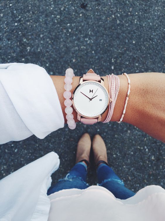 a watch with a pink leather band and pink bracelets for a feminine look