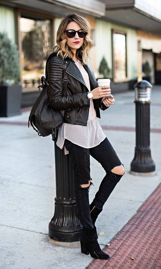 black distressed jeans, black suede booties, a white shirt, a black moto jacket and a backpack