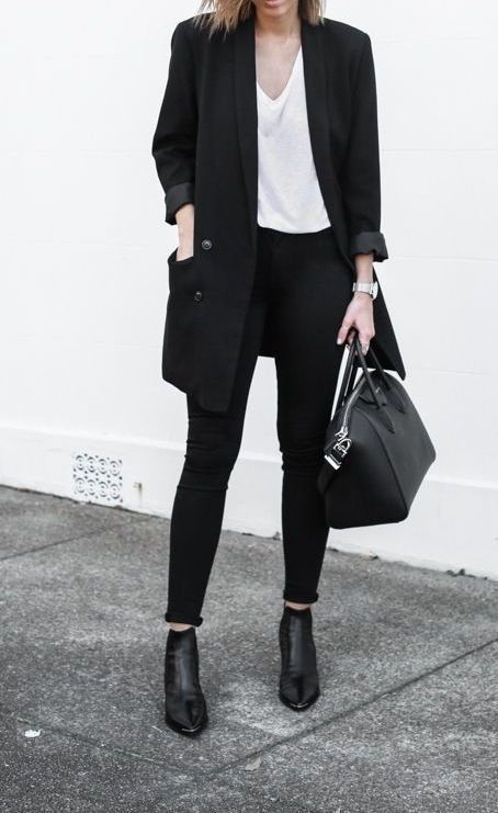 almost all-black work look with black jeans, a white oversized top, a black long blazer, black boots and a bag