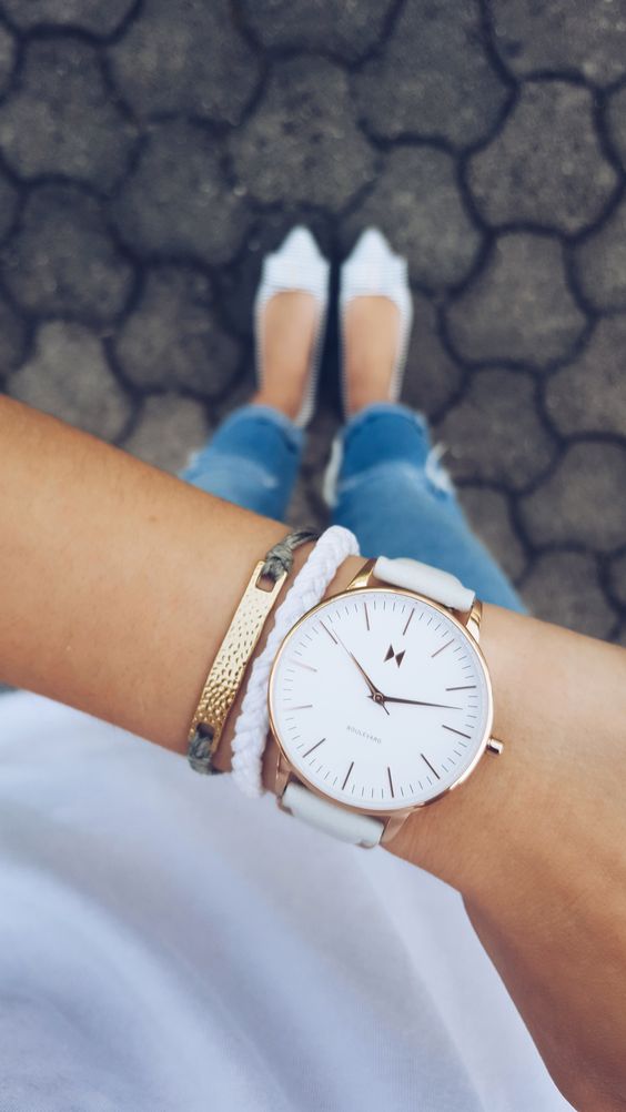 a large watch on a white leather band with a couple of matching bracelets accentuates your look