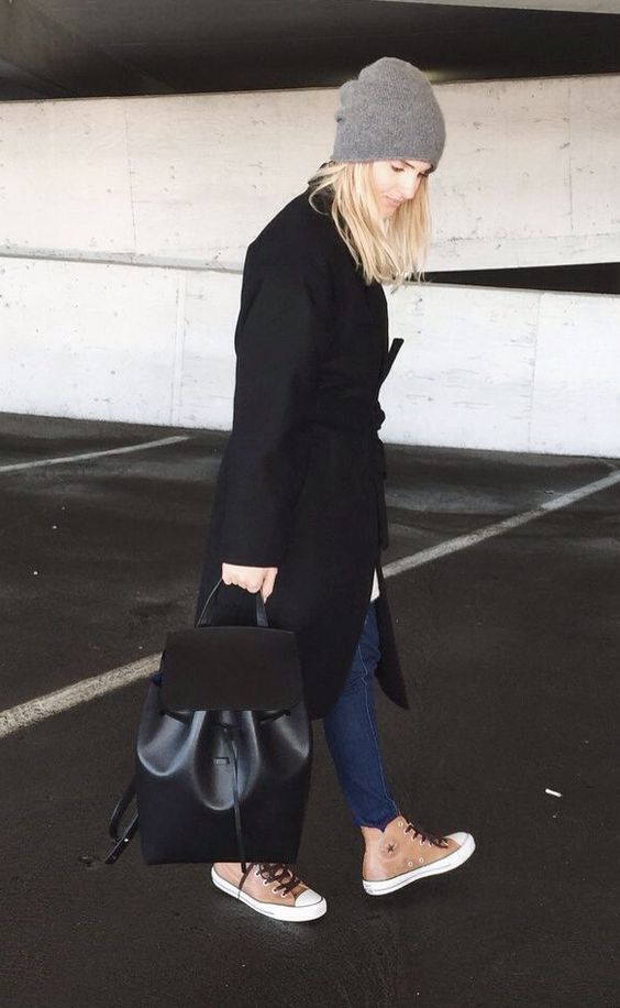 blue jeans, a black coat, high sneakers and a black leather and suede backpack