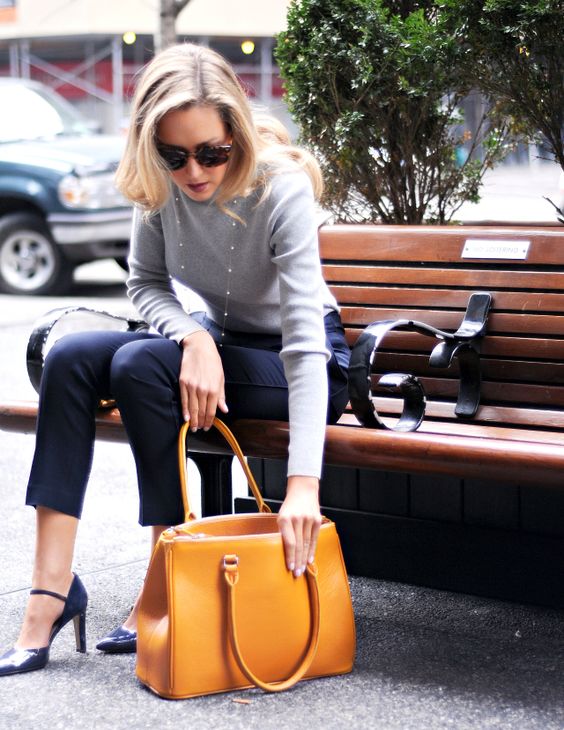cropped navy pants, a grey long sleeve top, navy shoes, a pearl necklace and a mustard yellow bag