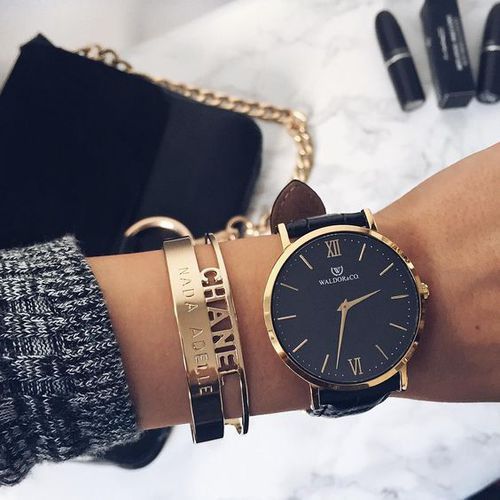 a large black and gold watch and gold bracelets to highlight it