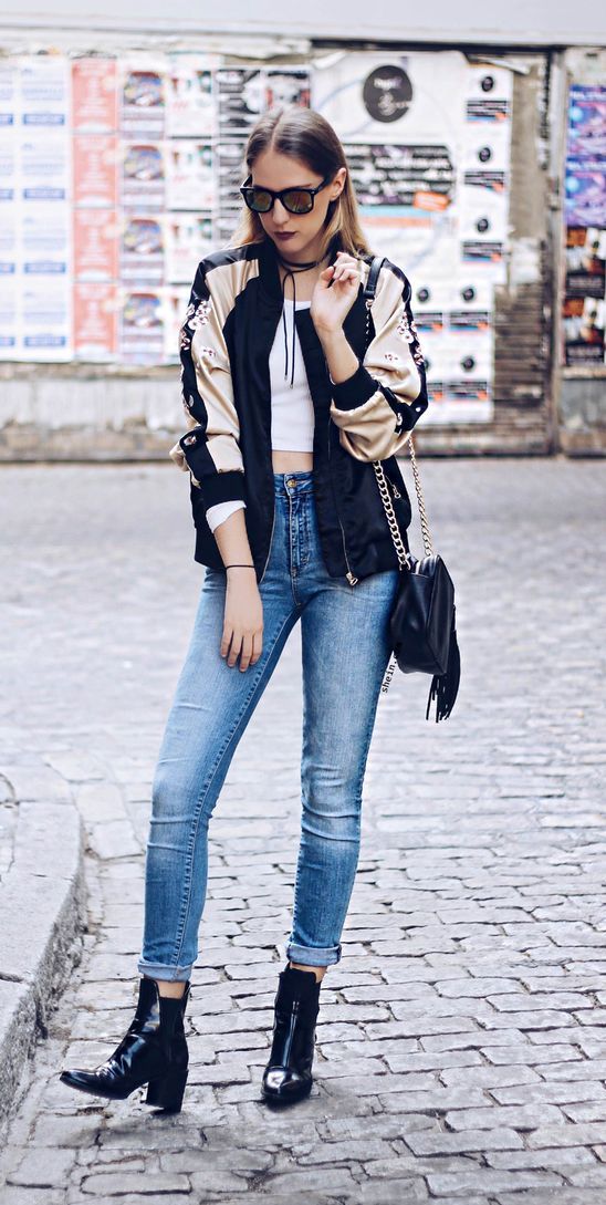 high waist blue jeans, a crop top, an embroidered bomber jacket and black leather boots
