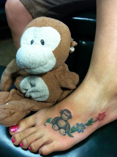 Black and white monkey tattoo with colorful flower tattoo on the foot