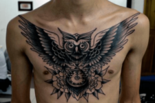 Black owl and clock tattoo on the chest