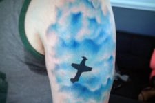 Blue clouds and plane tattoo on the hand