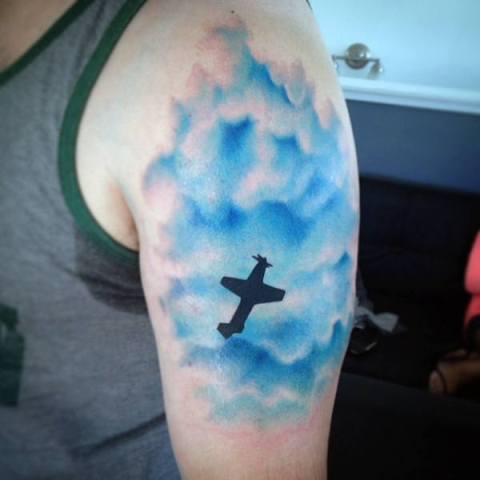 Blue clouds and plane tattoo on the hand