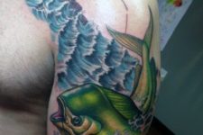 Green fish tattoo on the arm