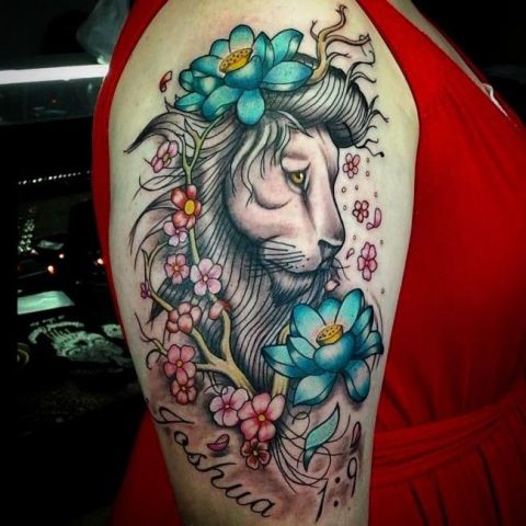 Lion with blue flowers tattoo on the arm
