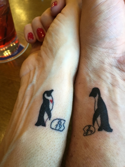 Matching penguin tattoos on the wrists