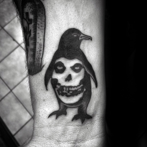 Penguin and skull tattoo on the wrist