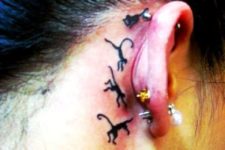 Tiny black monkey tattoos behind the ear