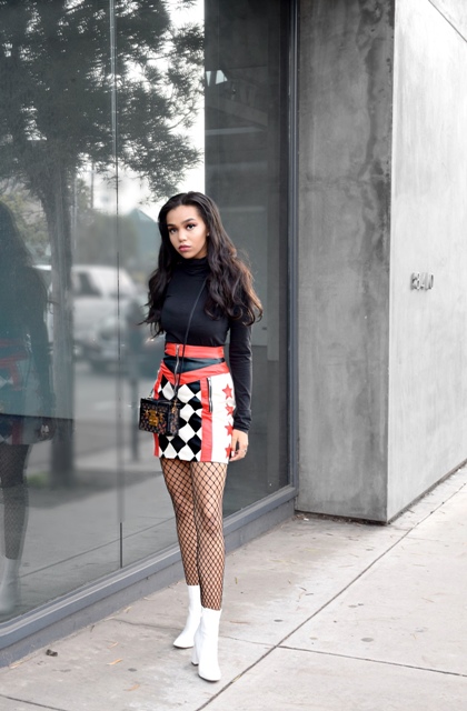 With printed leather skirt, black turtleneck, white boots and mini bag