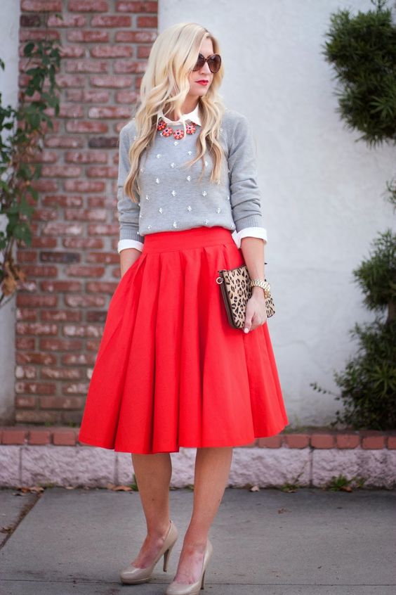 nude heels, a red midi skirt, a white shirt, an embellished grey sweater and a statement necklace for a holiday look