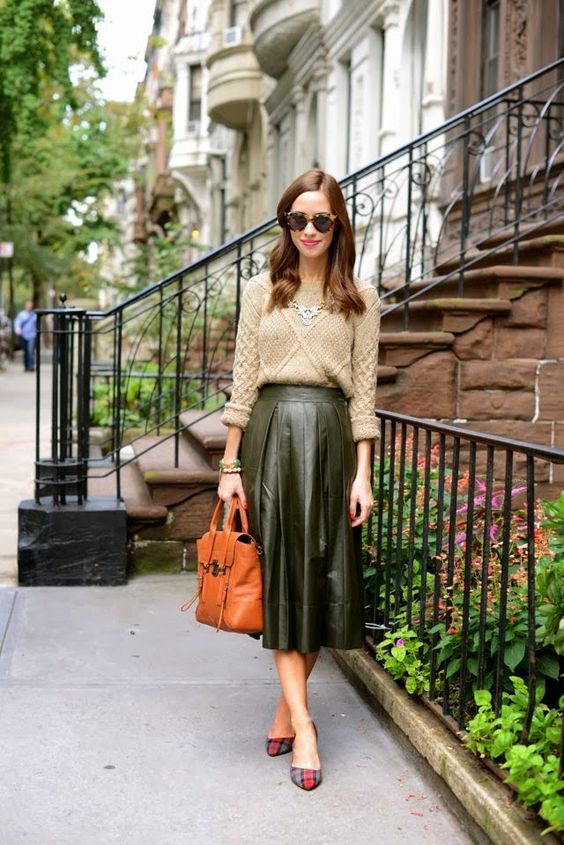 a green pleated midi leather skirt, a neutral sweater, a statement necklace and plaid heels