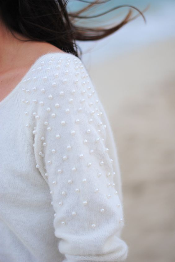 a white sweater decorated with pearls on the sleeves is a feminine idea