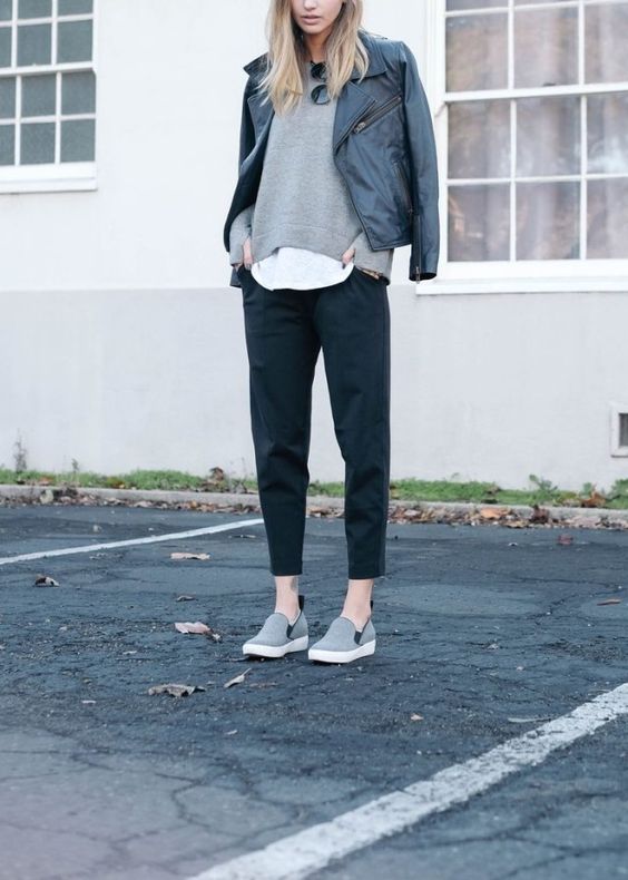 black cropped pants, a grey sweater over a top, grey flats and a black leather jacket