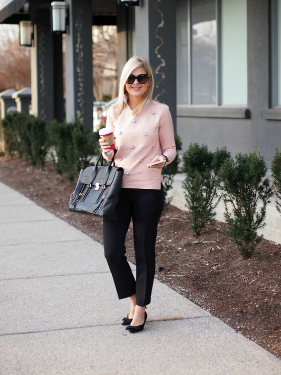 black trousers, a pink embellished sweater, black suede bow heels and a bag