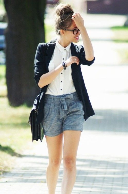 grey shorts, a white shirt with black buttons, a black blazer and a bag