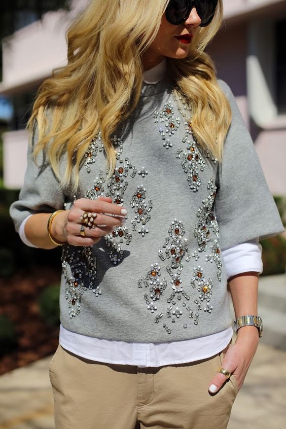 neutral pants, a white shirt and a grey embellished sweater